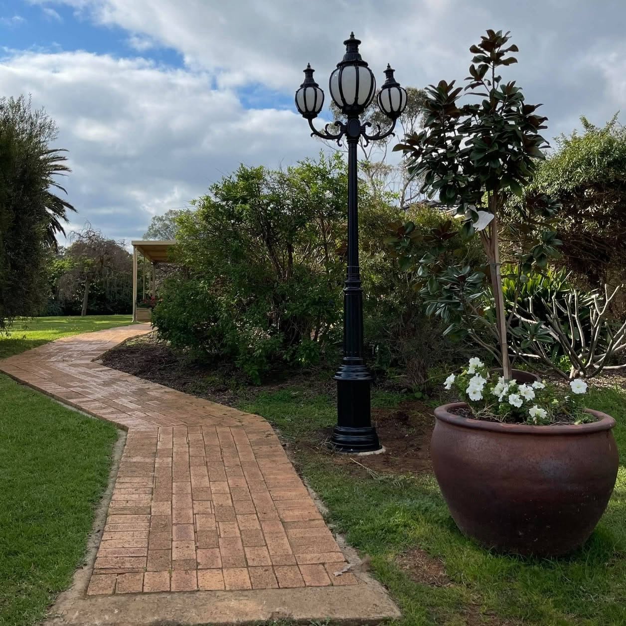 Wide view of the finished lamp post beside a curving brick path